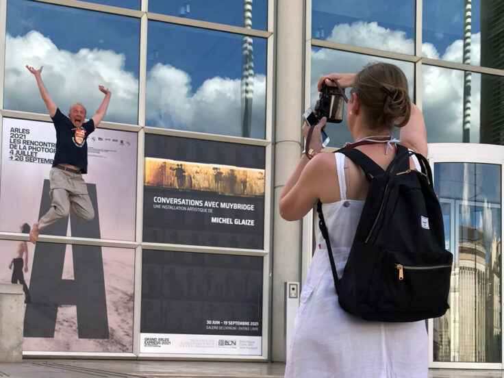 Michel Glaize sautant très haut devant l'affiche de l'installation à Carré d'Art, l'été 2021